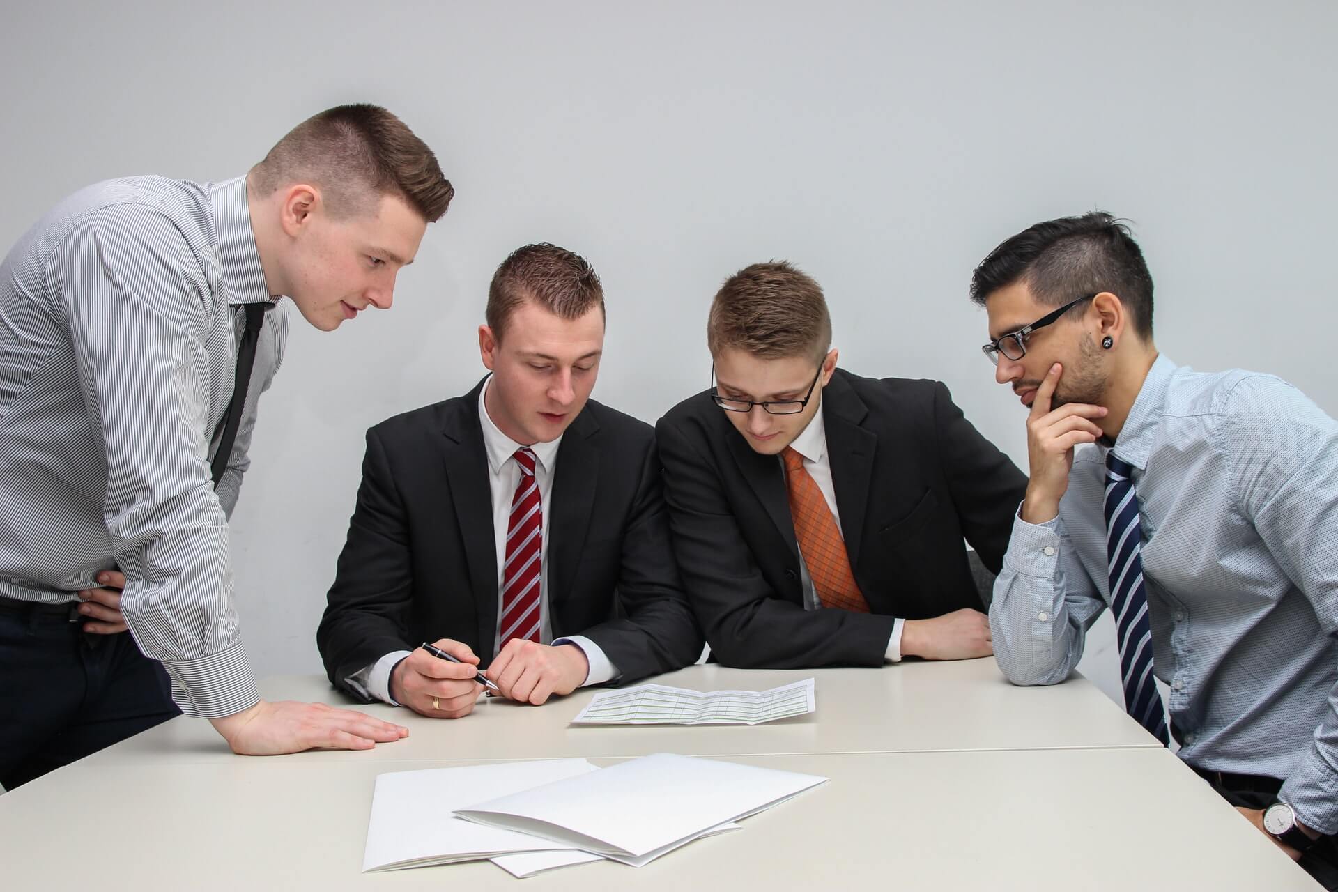 four men looking at a document