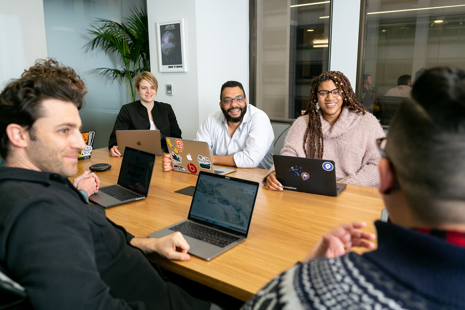this image shows a team of graphic designers with laptops discussing a graphic design project in a meeting room