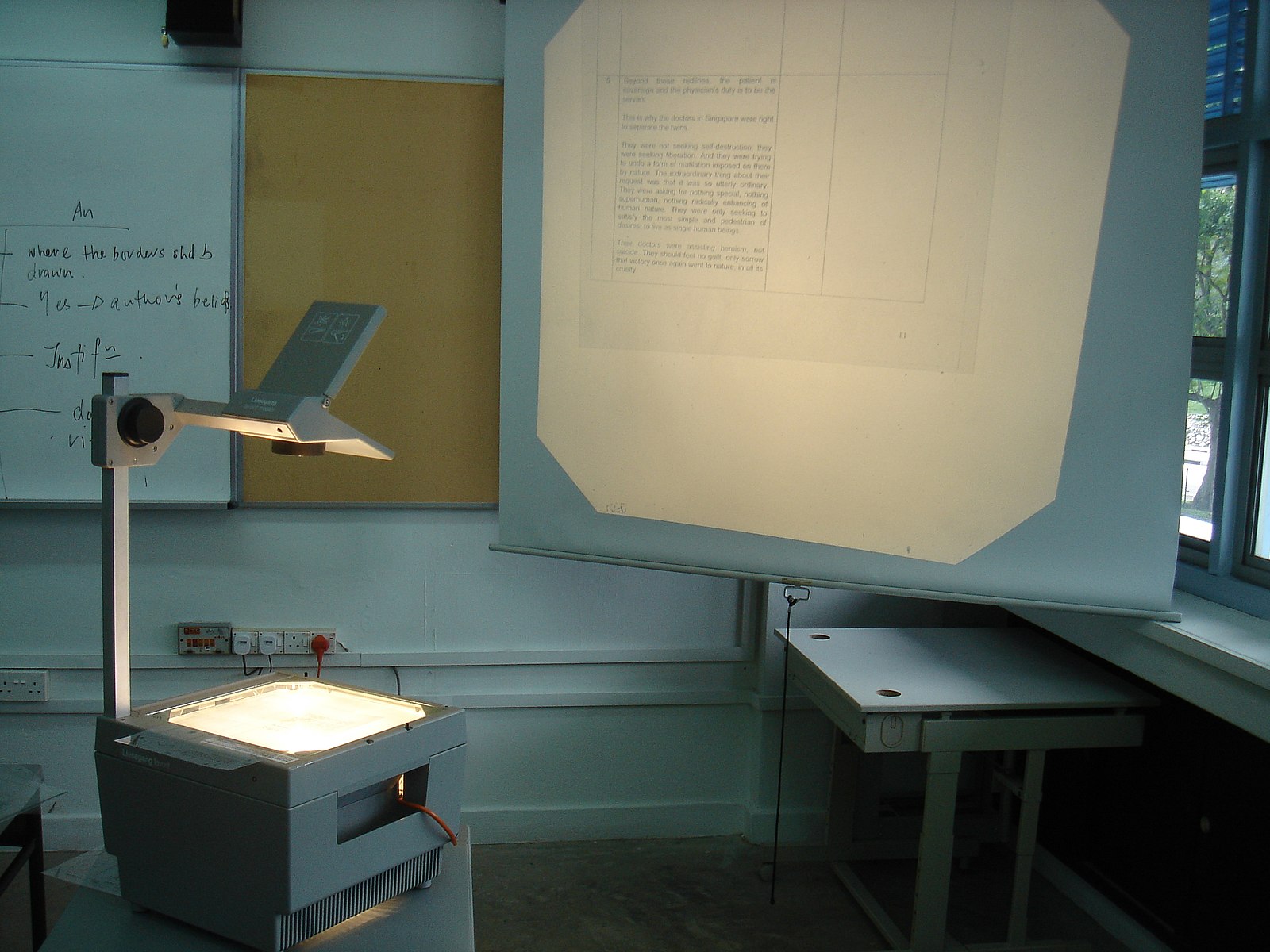 an overhead projector projecting onto a screen likely in a classroom