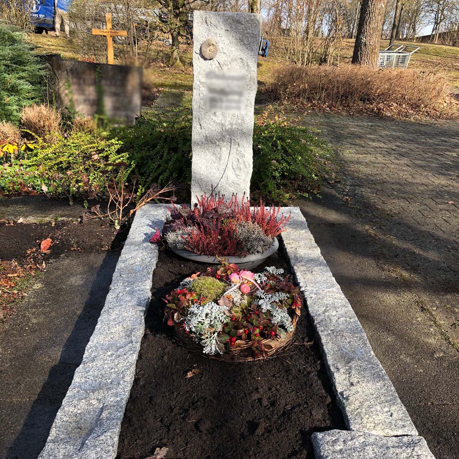 Einzelgrabstein mit Beschriftung und Kreuz