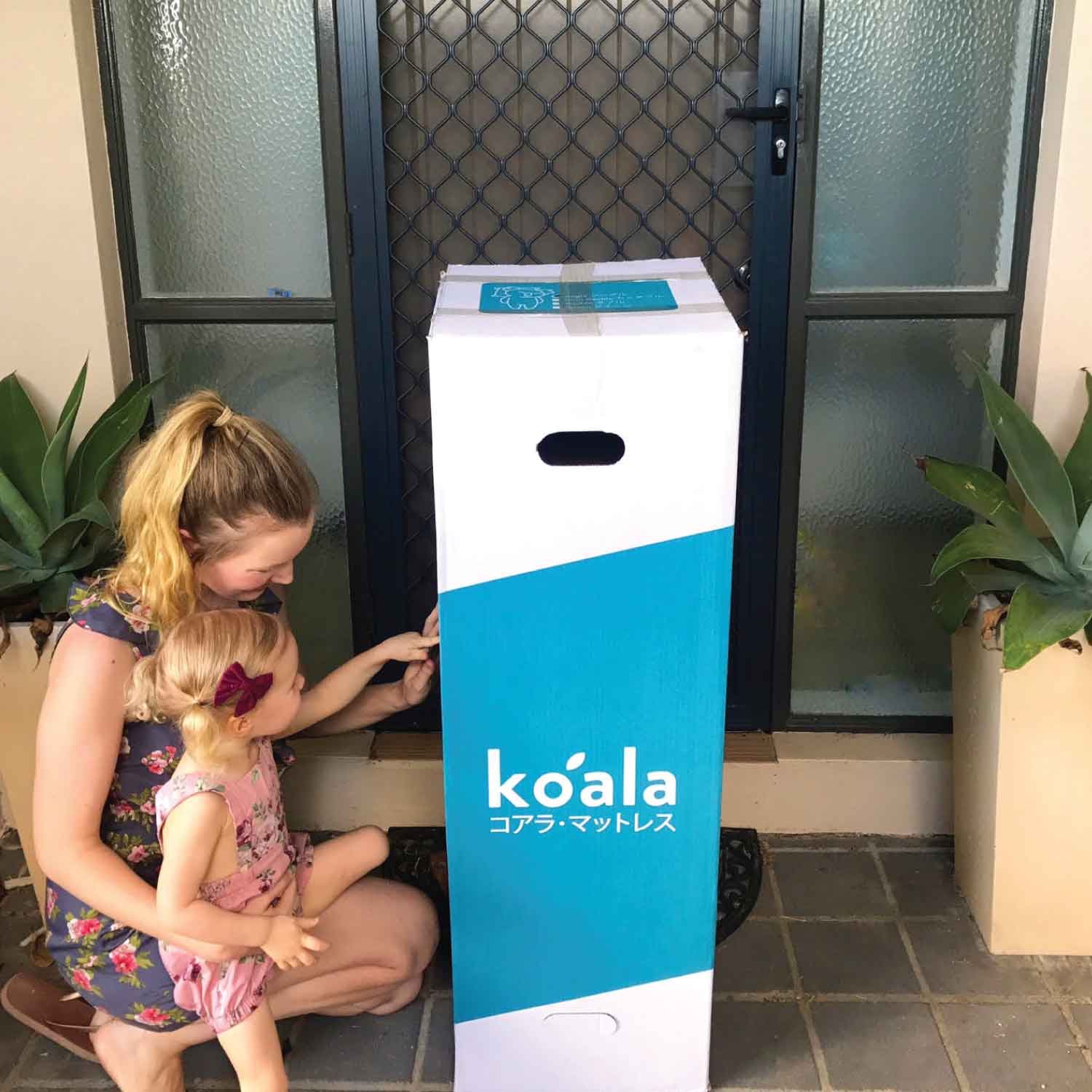 The Koala mattress in a box on a door step with mother and child