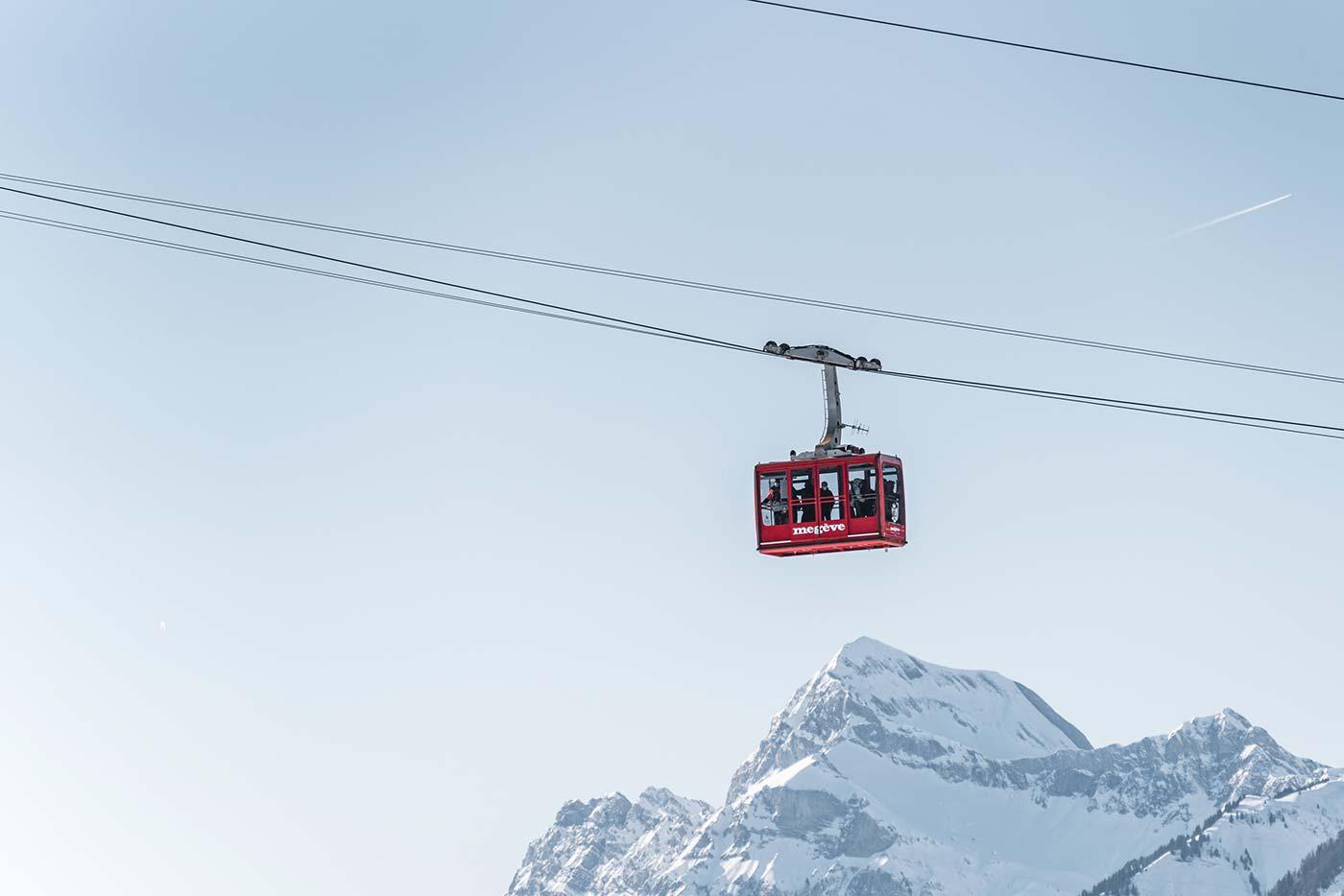 A red cable car above a snowy mountainDescription automatically generated with low confidence
