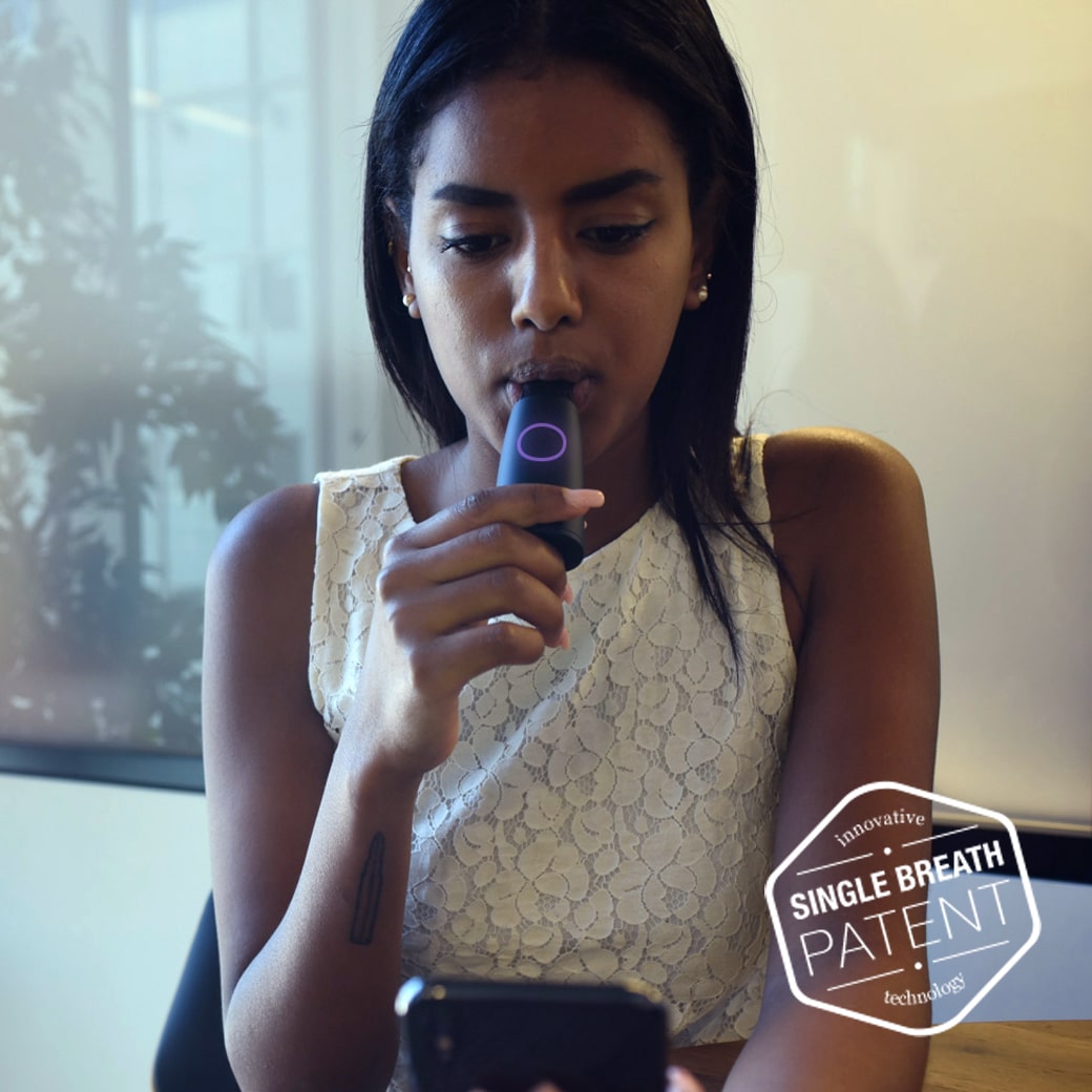 woman taking a breath through the lumen metabolism tracker connected to phone