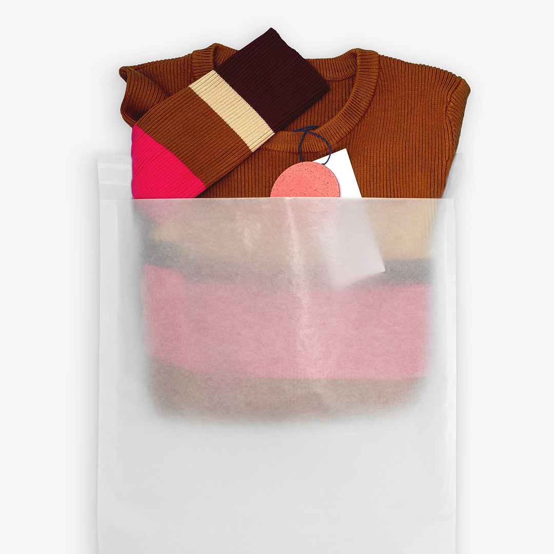 A striped sweater in a vela paper transport bag