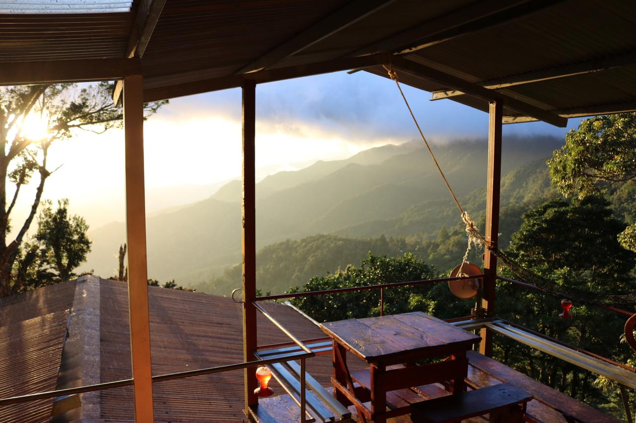The open balcony of the Lost and Found Hostel, looking out onto a green valley, the sun is setting