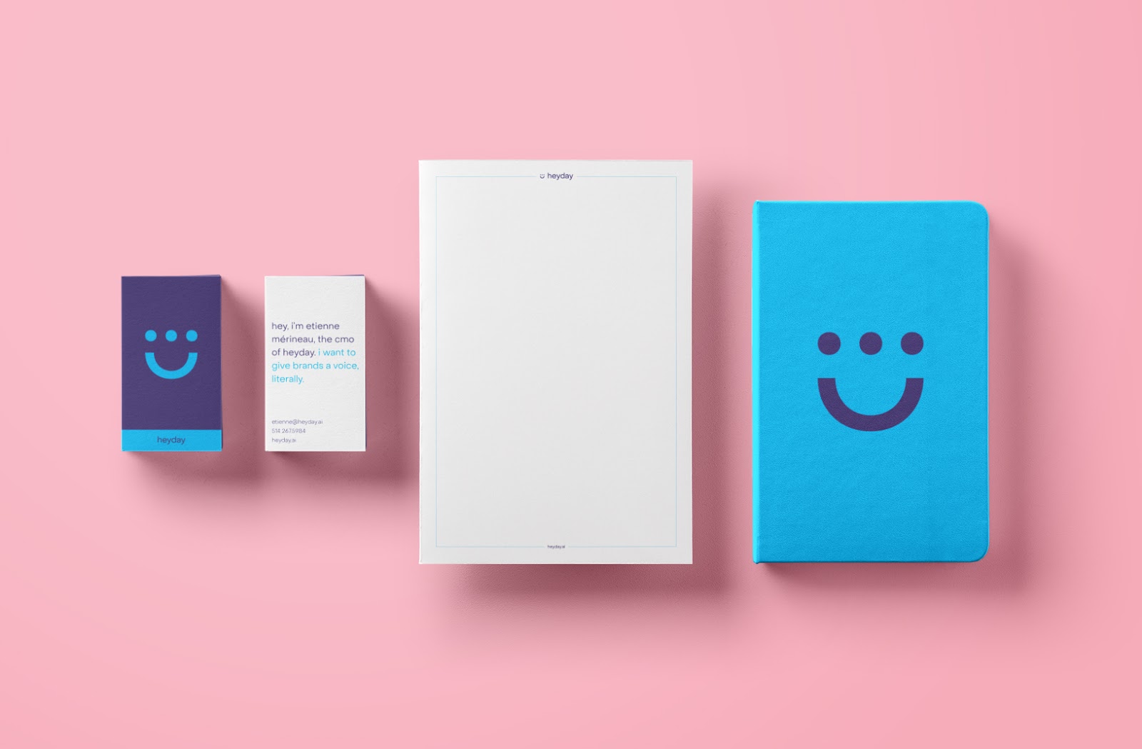 Heyday stationery such as business cards and notebooks put on a pink background.