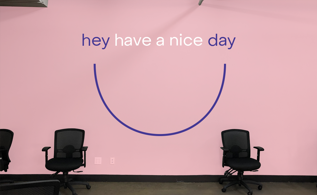 Hey have a nice day are written on a pink wall.