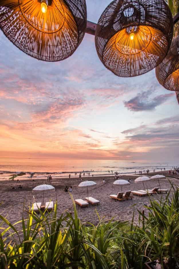 woven hanging lamps and view of beach chairs on the beach at dusk in Bali Indonesia