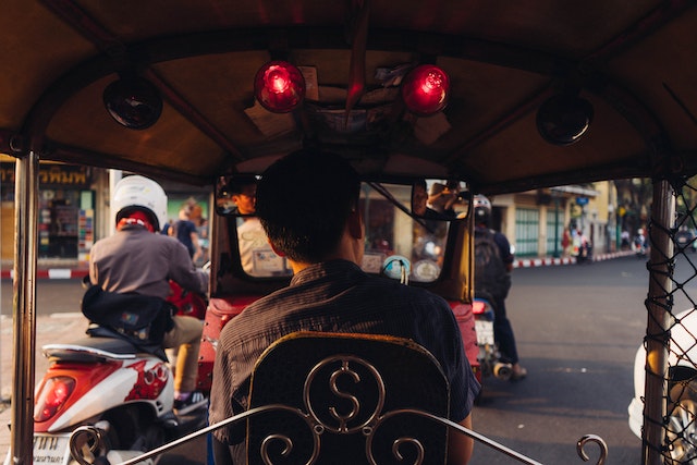 Man riding in back of tuk tuk in Bangkok, Thailand