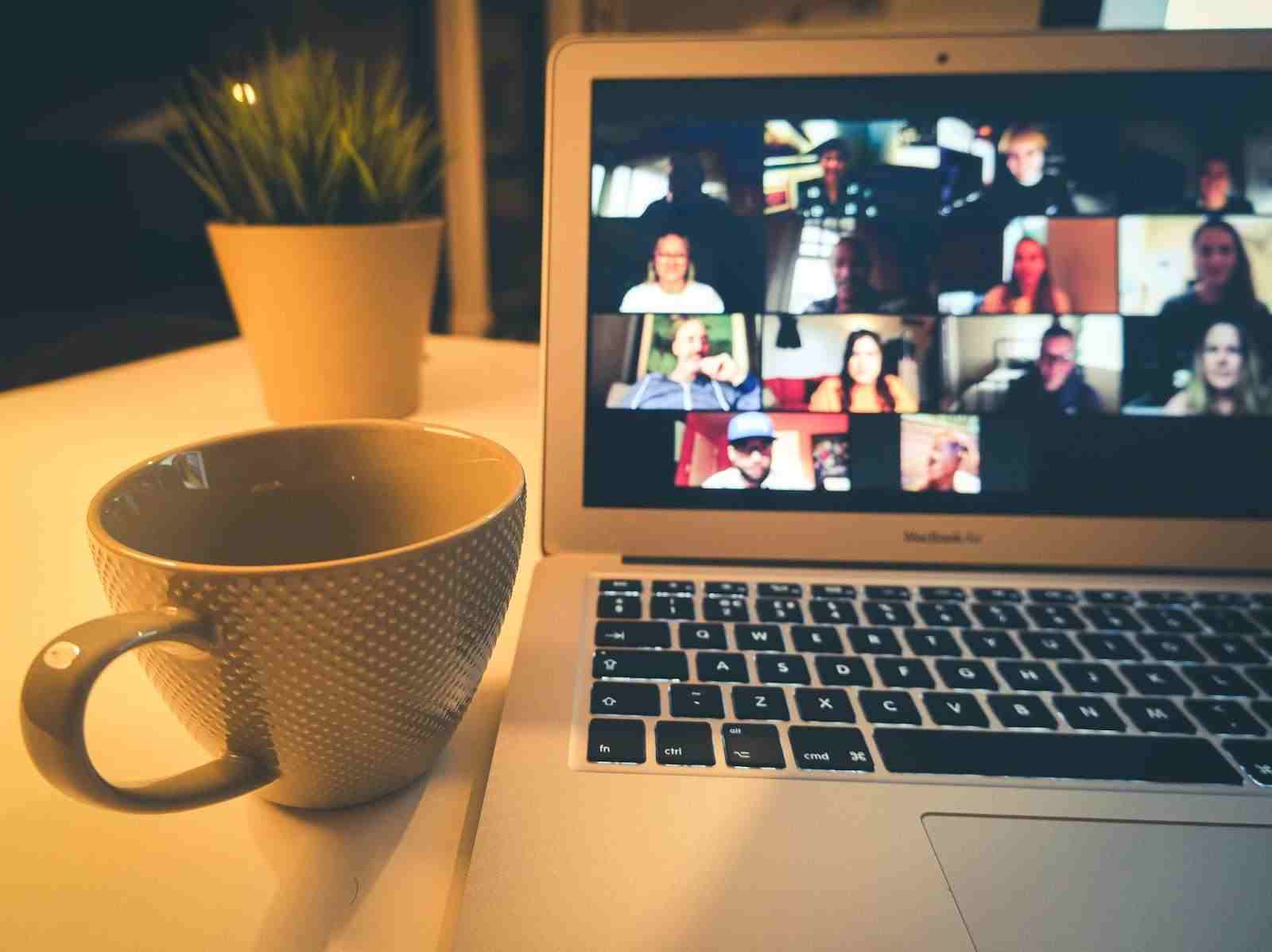 freelancer in an online meeting with mug at a desk