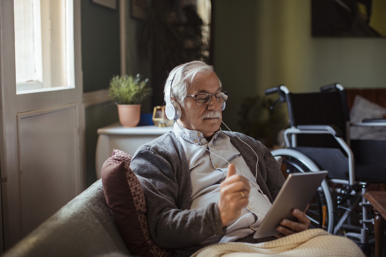 Older gentleman using iPad with headphones. Credit: iStock.com/Geber86
