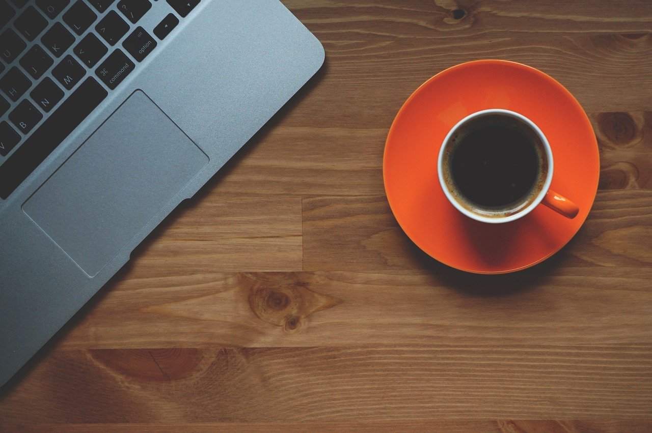 Cup of coffee next to computer.