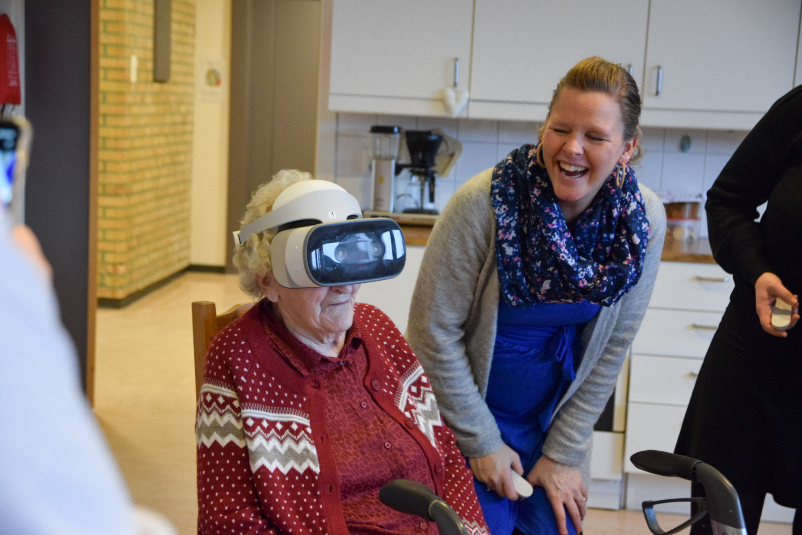 Eldre dame prøver VR-briler. Yngre dame står ved siden av og smiler.