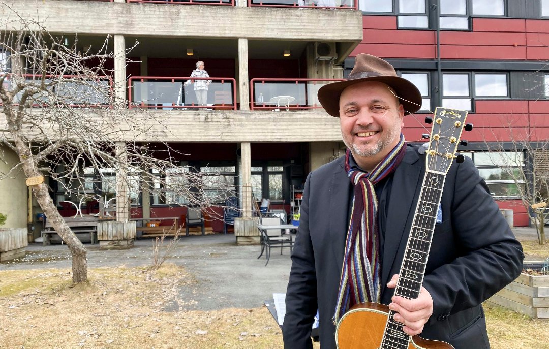 Bernt Torp står med gitar foran Brumunddal Sykehjem etter utendørskonsert