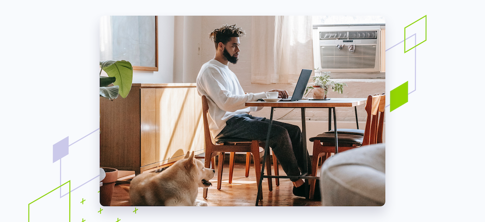man at home working on laptop with dog next to him