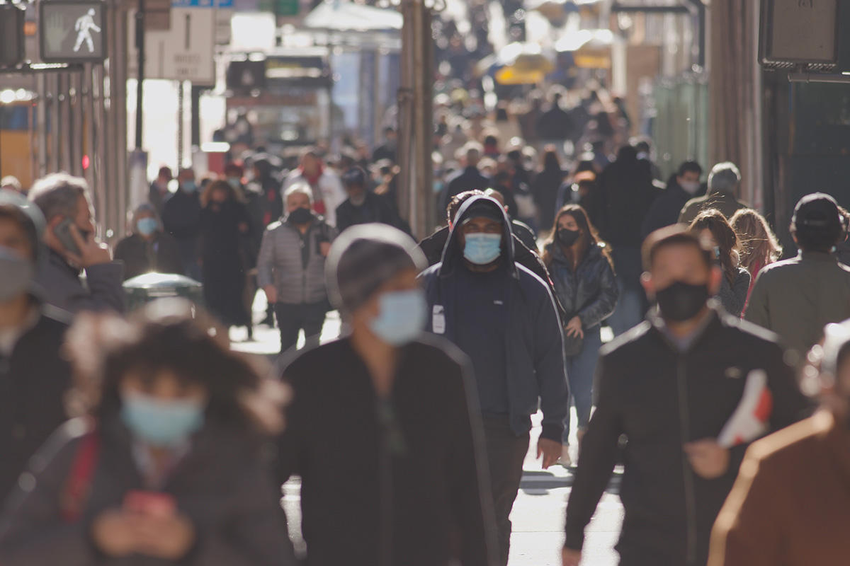 crowds of people walking down a street wearing masks in the uk