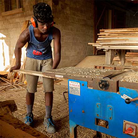 Mann in Afrika am Holz schneiden mit Sicherheitsschuhen