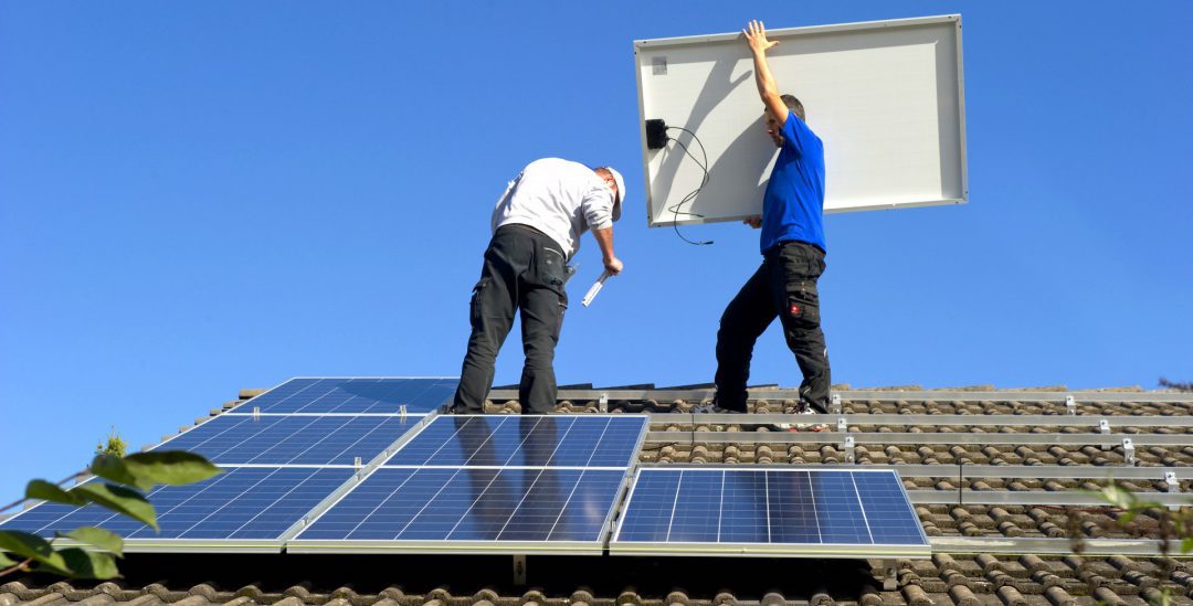 Zwei Männer auf einem Dach, die eine Solaranlage installieren