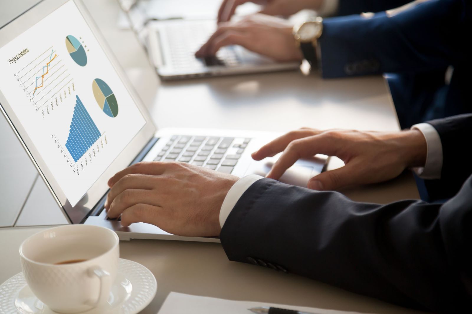 hands on a laptop with an image of analytics on the screen