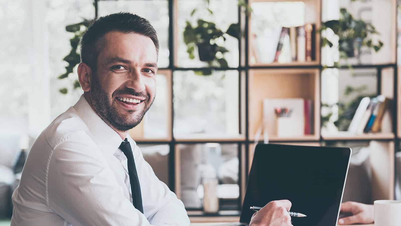 Man at computer smiling for the camera.