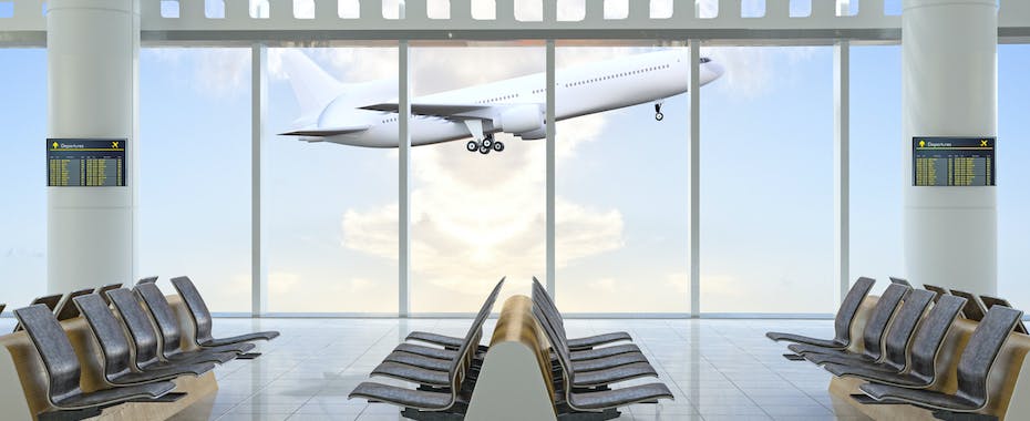 Plane taking off outside window of empty airport