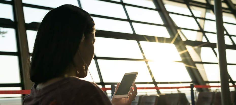 Woman checking phone in sunlit airport