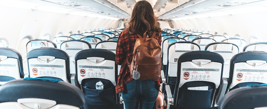Ariline passenger walking towards exit of empty airplane