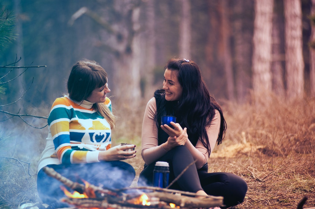 Two women in front of a fire in the outdoors
