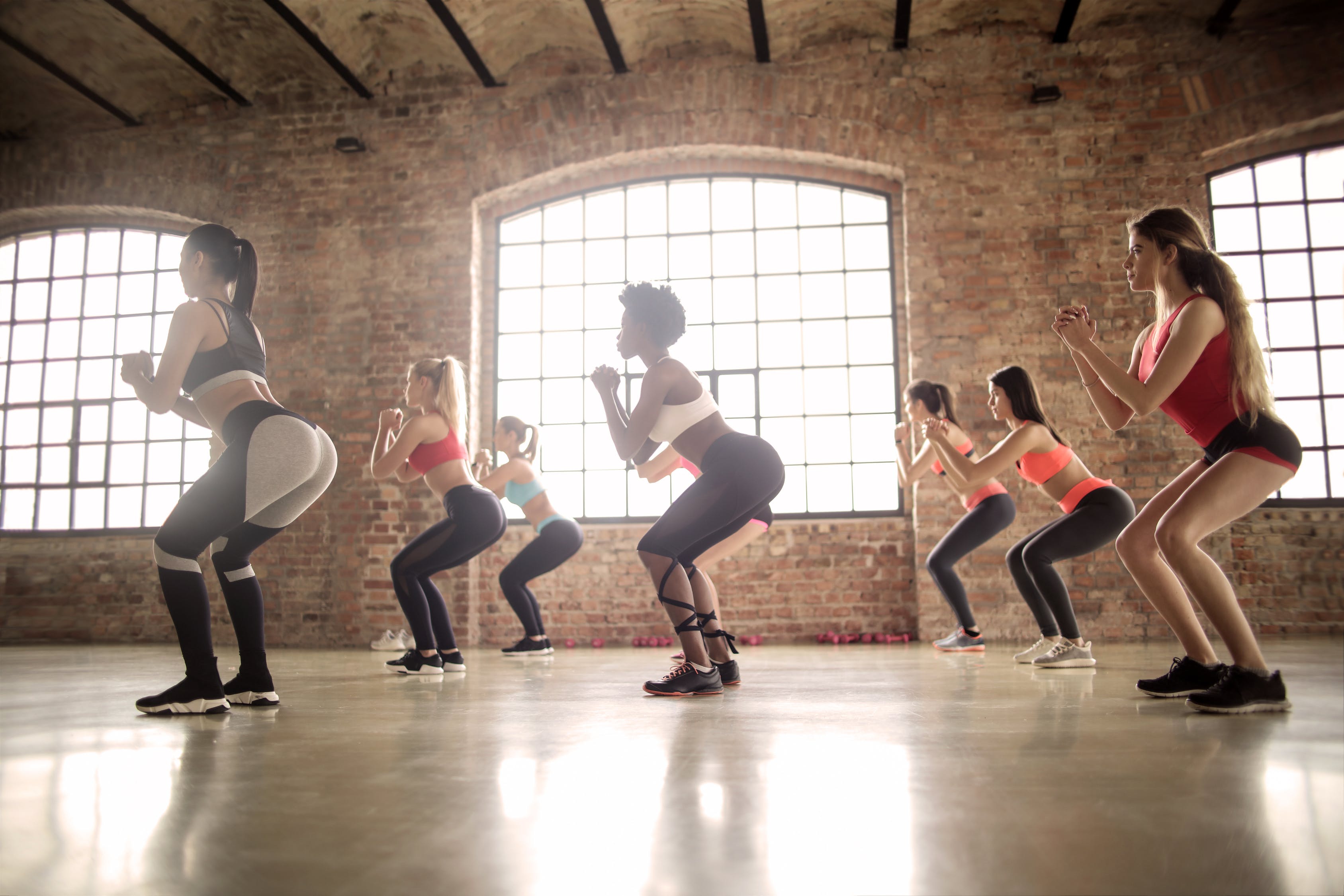 Women squat in unison during an exercise class.