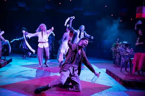 Ivan Mihailović (Solider), a white man kneeling on the ground in foreground with other actors in background, covered in blue light