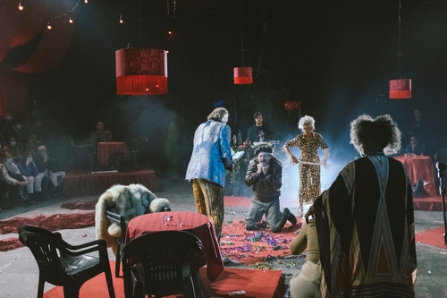George Drance (Agamemnon), an older white man, being executed while other performers watch