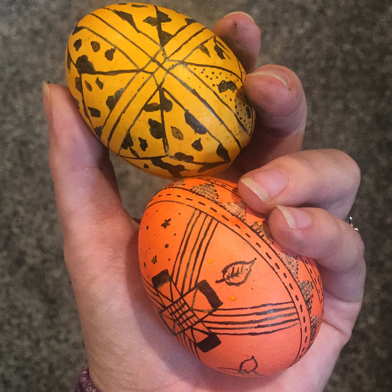 Two partially decorated eggs with wax still on them