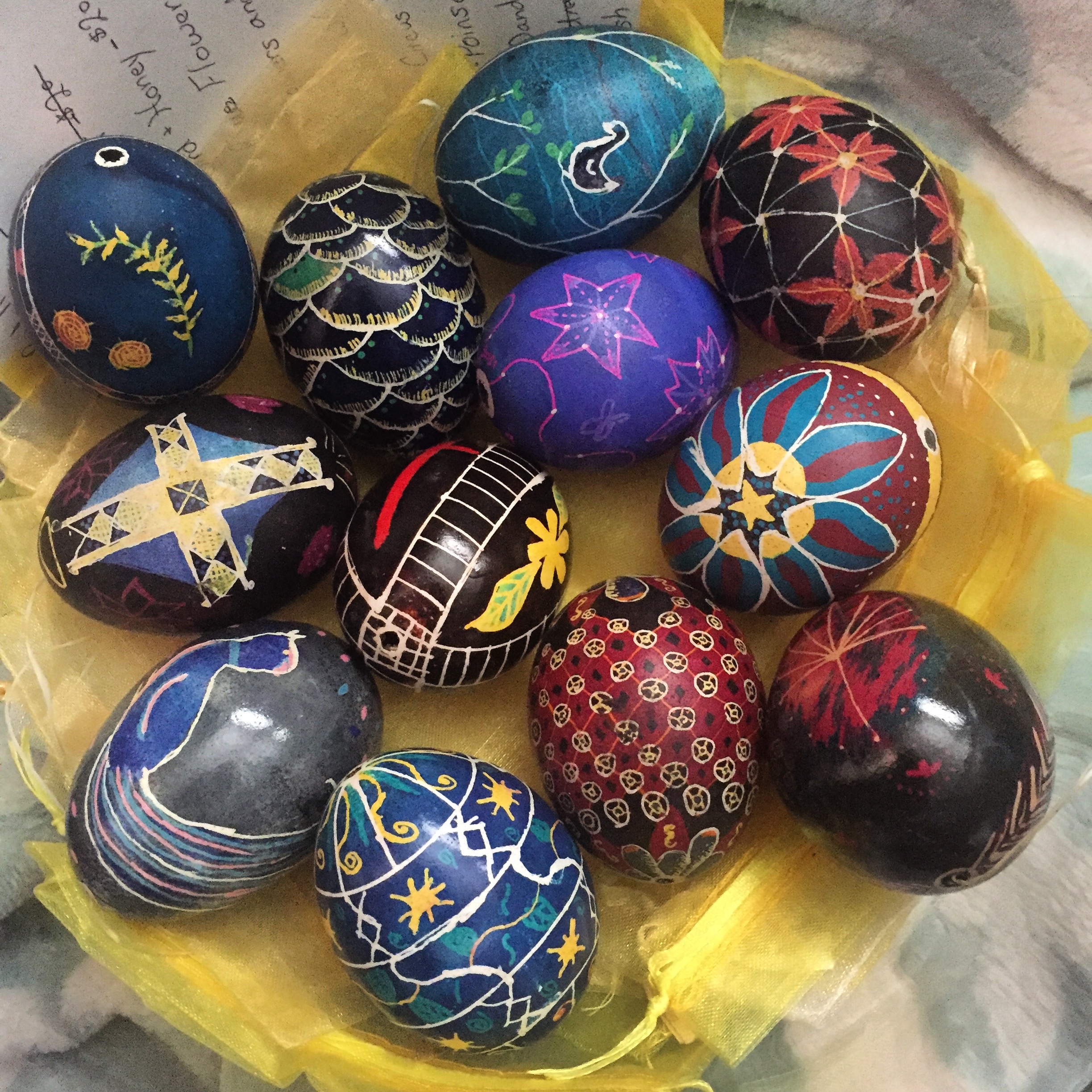 A bowl of a few different decorated eggs of differing designs and color