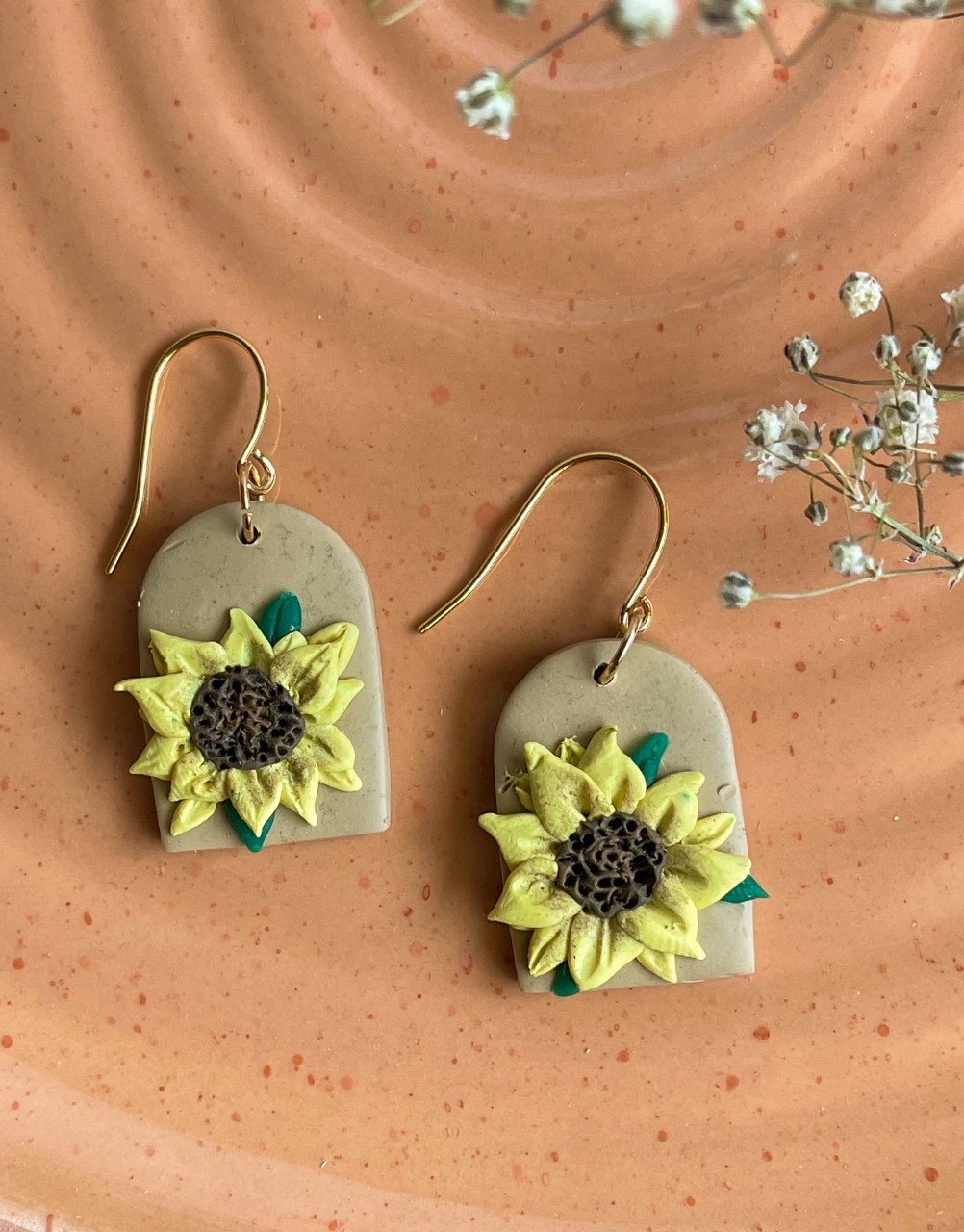 Arch-shaped polymer clay earrings in tan with a sunflower design.