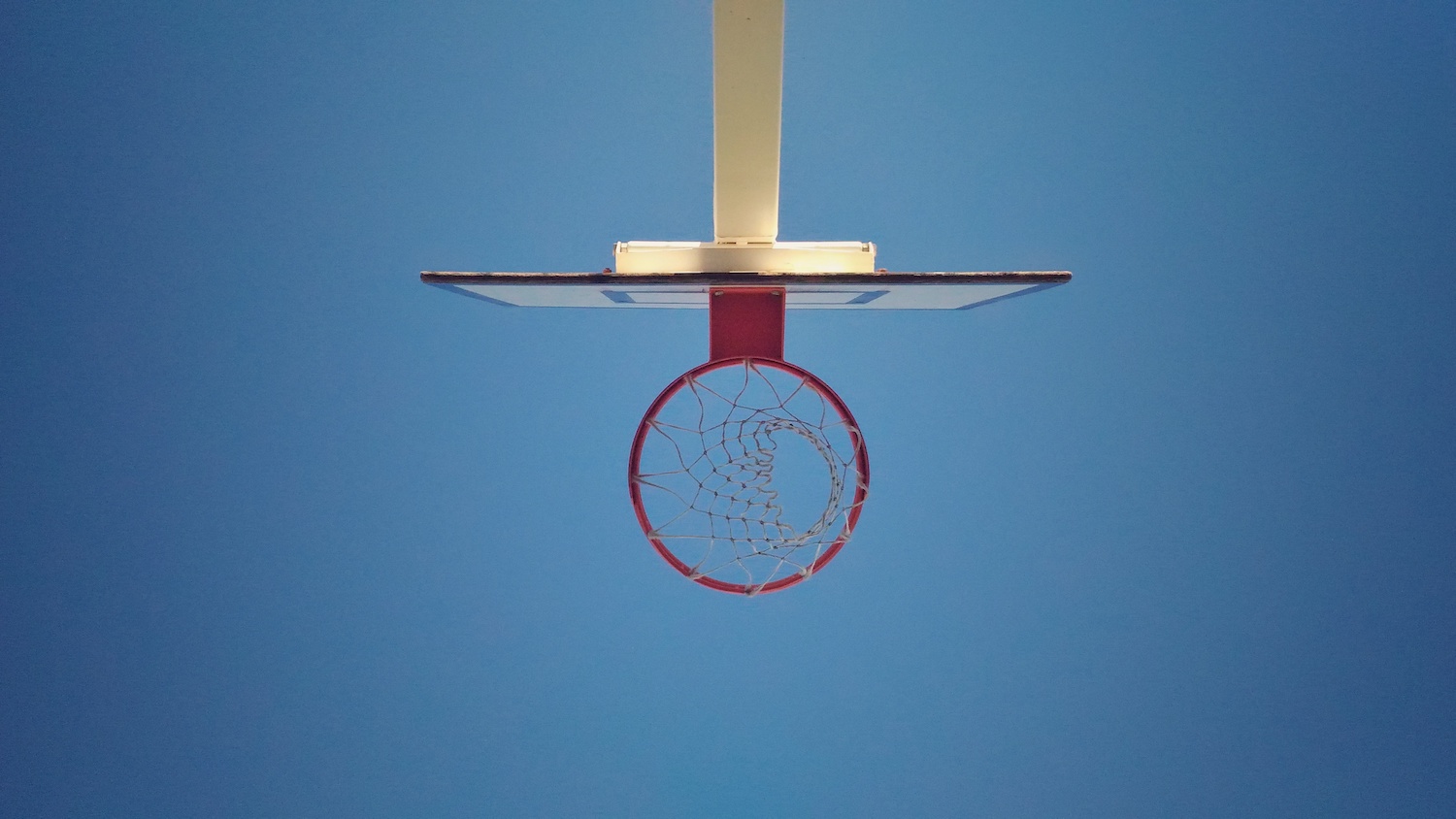 Basketball basket viewed from bottom to top against a blue sky