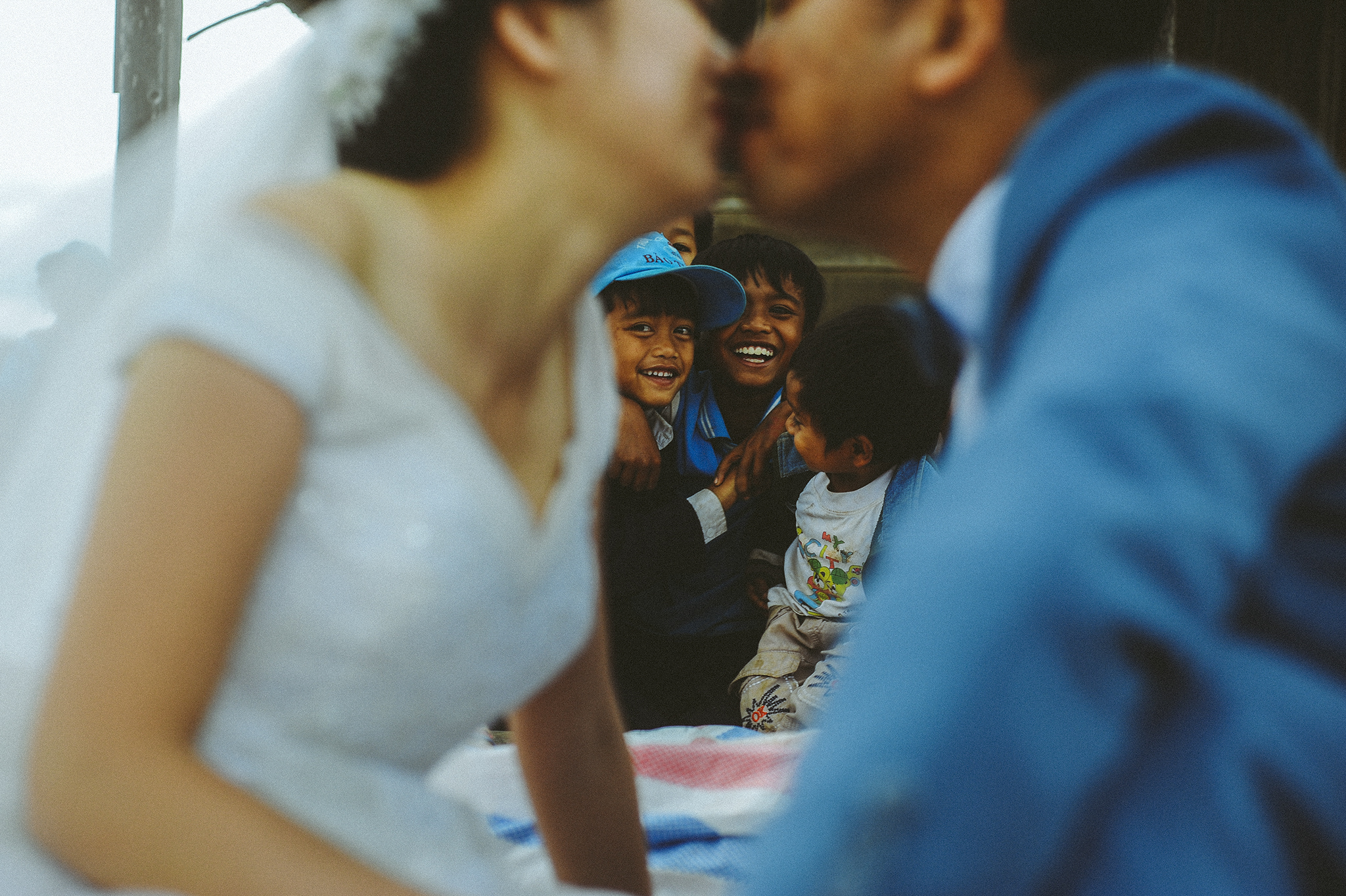 Bride and groom kissing with kids in the background