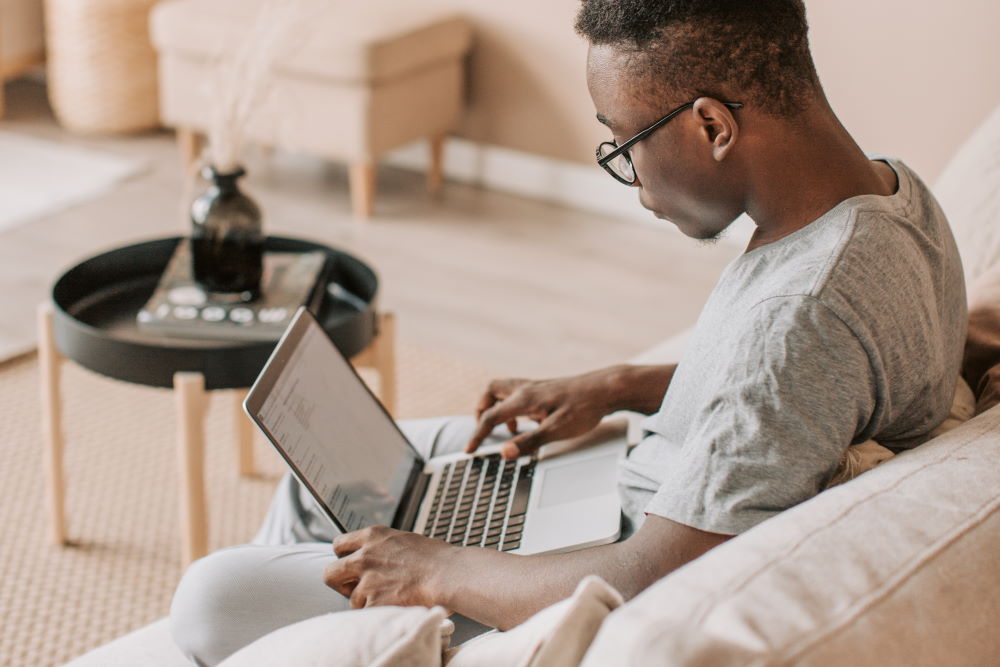 A young man watching Derek Prince on his laptop at home