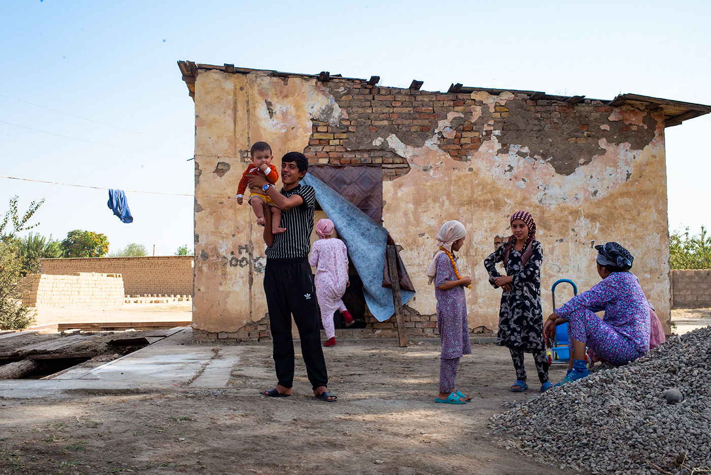 A happy family with a father holding a baby two girls playing around and the mother sitting aside