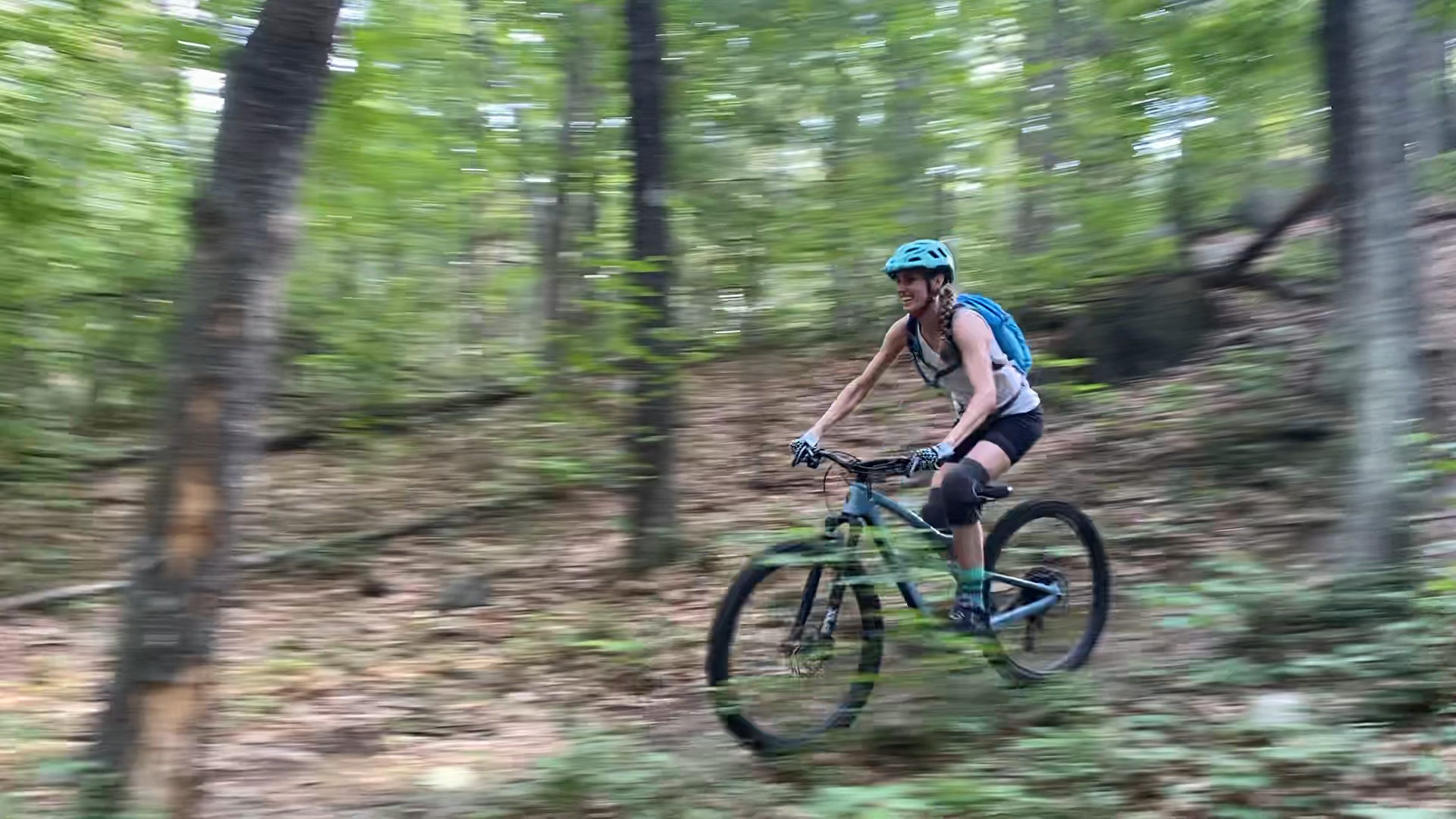 Becky is wearing a blue helmet while riding downhill on a mountain bike.