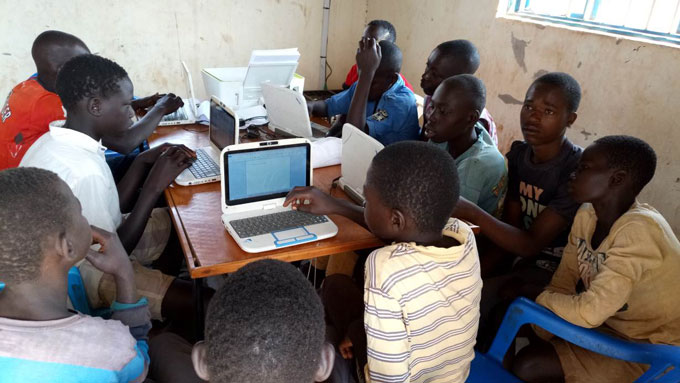 Students gather around computers during ICT training for South Sudanese refugees in the West Nile region in Northern Uganda.