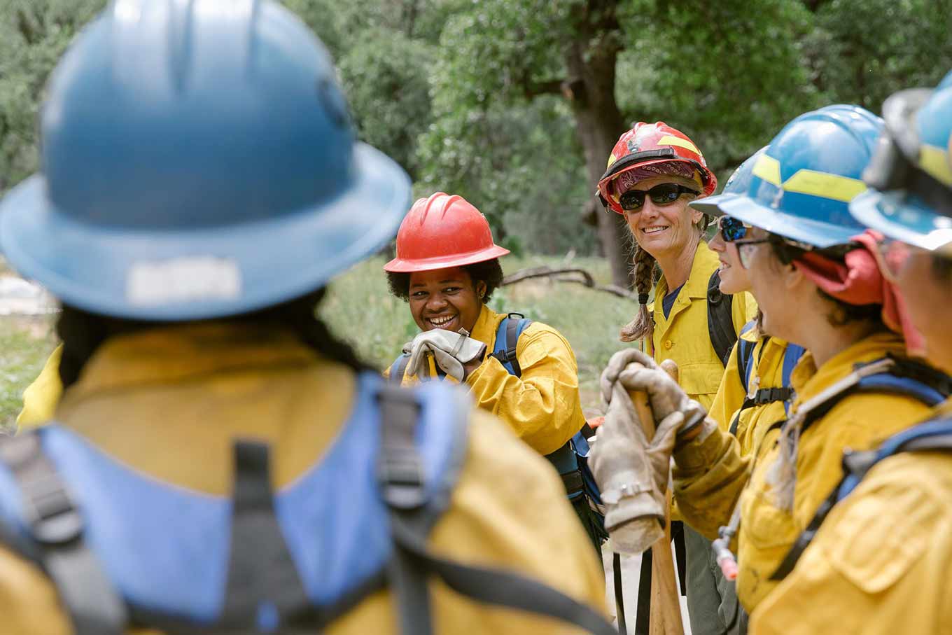 Tricia and another woman firefighter smile with more firefighters surrounding them