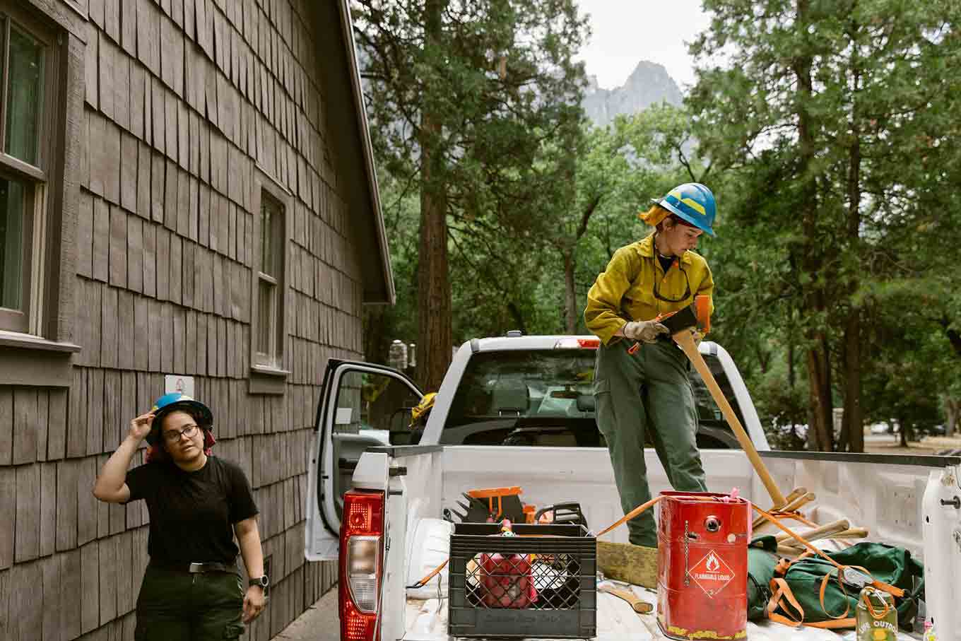 One firefighter passes another one that is on top of a pickup truck