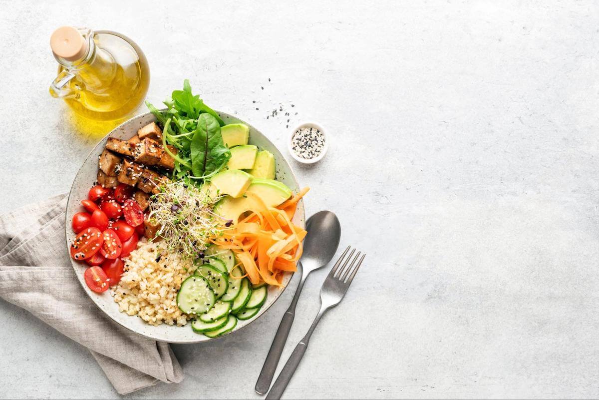Normal blood sugar levels: A bowl of rice and vegetables sitting on a table with utensils and a bottle of olive oil
