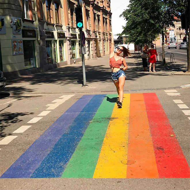 Woman crossing street on rainbow colored crosswalk
