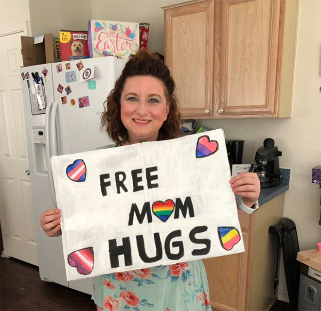 woman holding sign that says free mom hugs