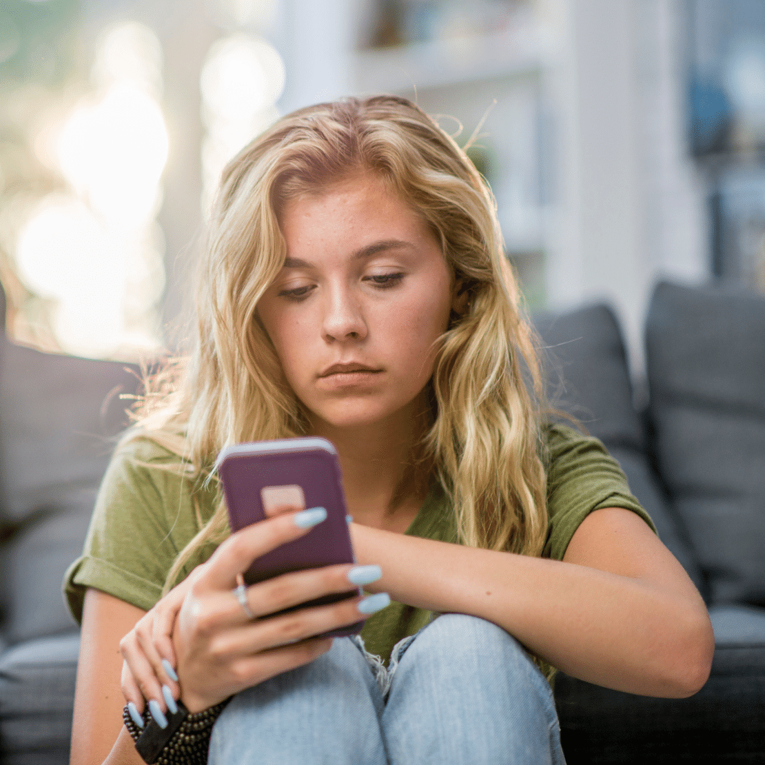 young woman looking sadly at phone