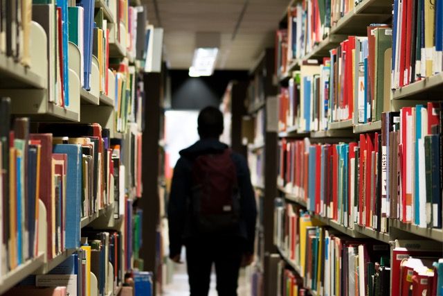 A student walks down an aisle in a libray.