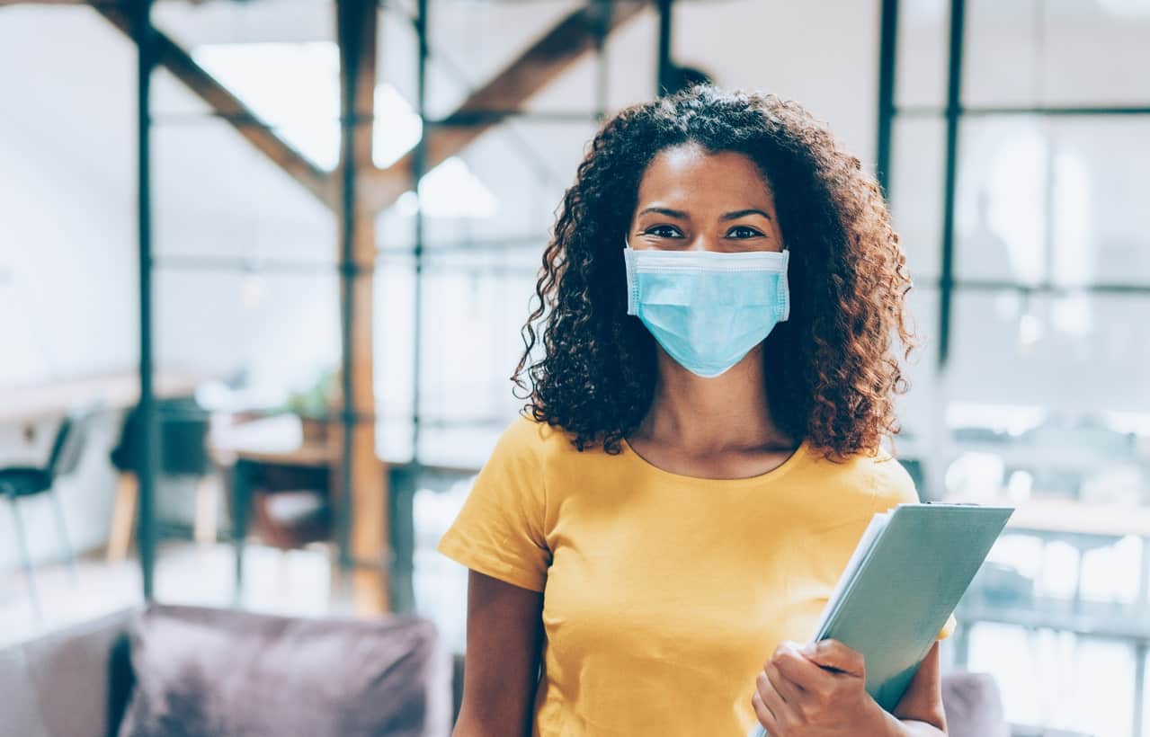 Lady in yellow shirt wearing a mask and holding a clipboard