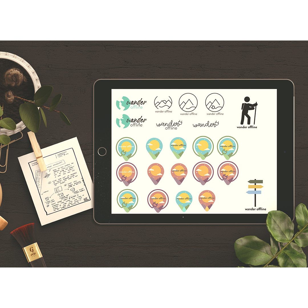 An ipad on a table showing navigational icons for a website. Fourteen icons in various colours of blue and orange with a yellow sun in the centre. Above those is a grid of logos for "wander offline" navigational app. Each show a mountain range. Two rows of eight logos.