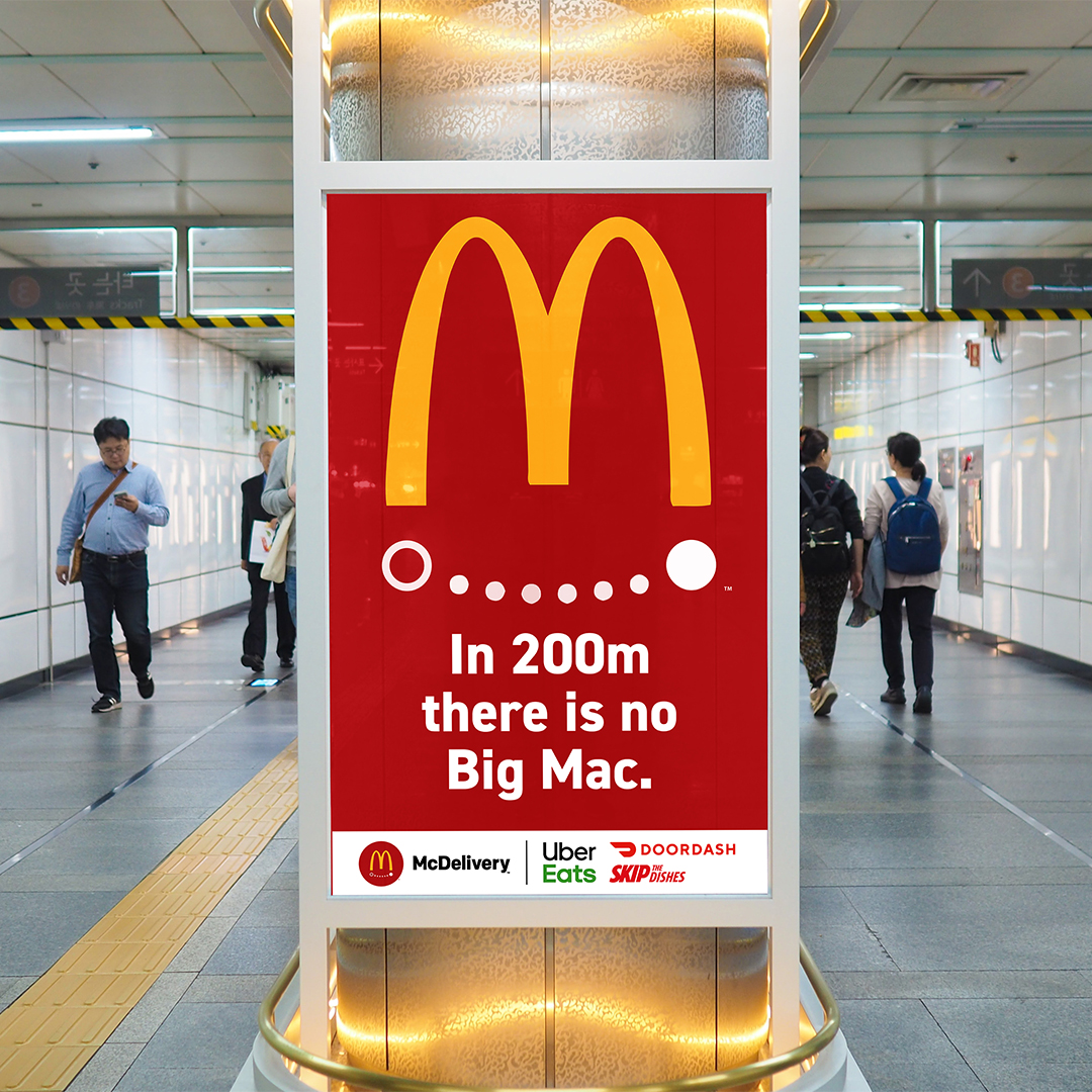 A subway poster advertisement for McDonalds. A red background with the Golden Arches drawn. Underneath are with dots that form a smile. The text underneath says "In 200m there is no big mac."
